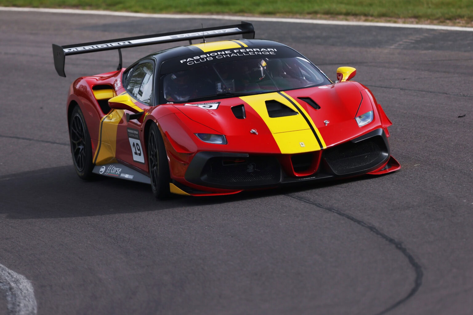 No 19 red and yellow Ferrari 488 negotiates a right hand corner in the Ferrari Club Challenge